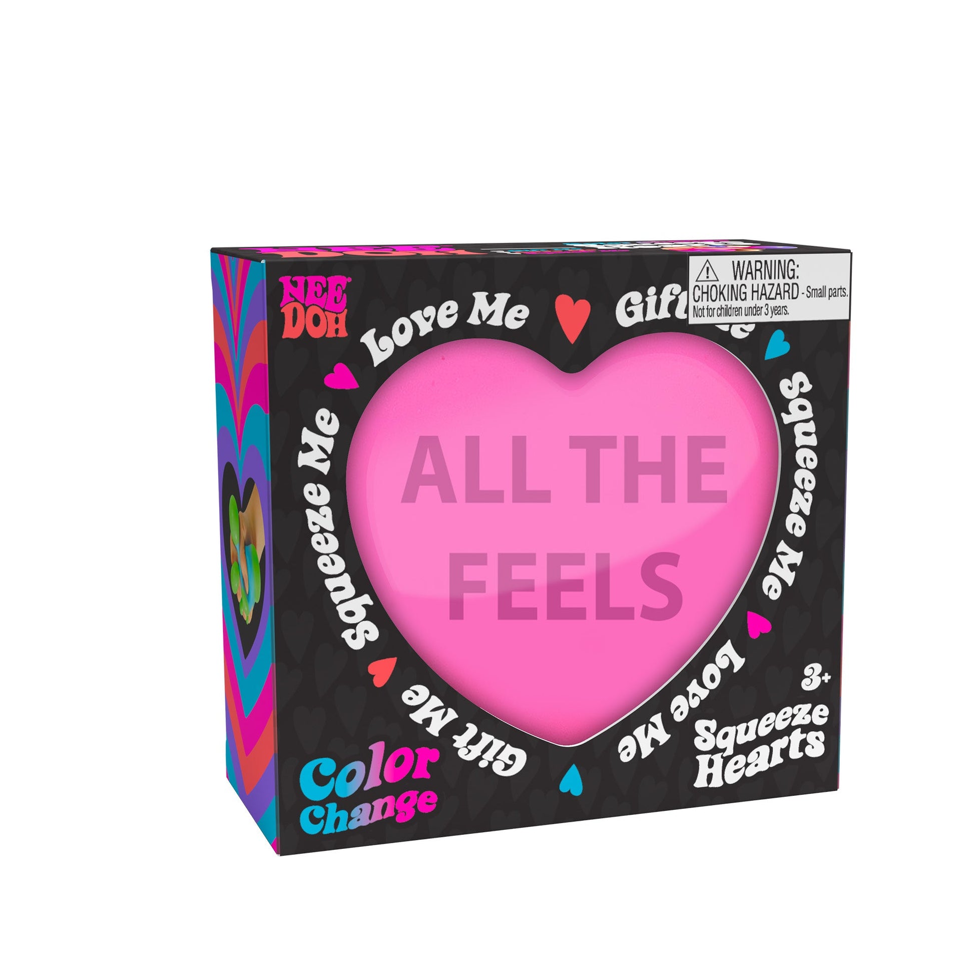 A boxed Color Change Squeeze Heart toy. The packaging is predominantly black with colorful accents, featuring phrases like "ALL THE FEELS," "Squeeze Me," "Love Me," and "Gift Me." The box also includes a choking hazard warning for small parts.